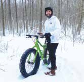 Cyclist standing with a fat-tire bike in a snowy forest.